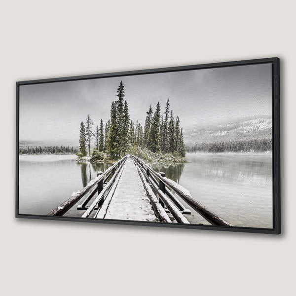 Framed Wall Art: Serene winter landscape Canvas Print featuring a snowy bridge leading to an island. Neutral color palette with pops of green. Perfect for home decor.