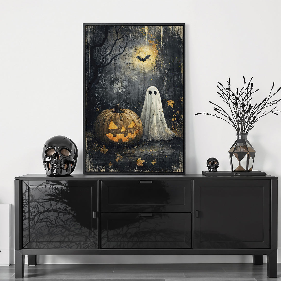 Framed Wall Art featuring a spooky Halloween scene with a pumpkin, ghost, and bat. Dark, moody color palette perfect for fall decor.