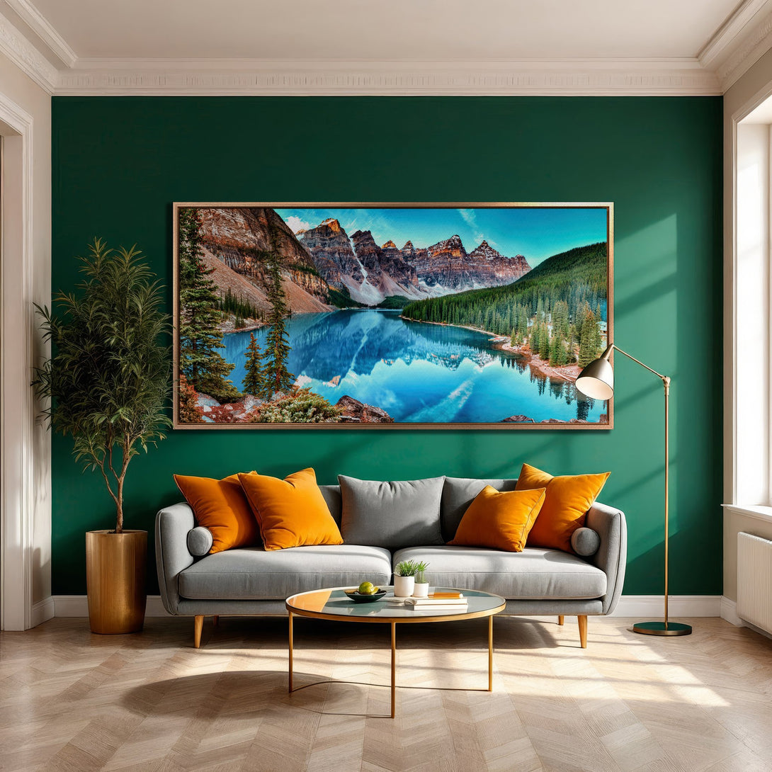 Framed Wall Art of a serene mountain lake scene in vibrant blue, green, and brown tones. Modern interior decor with a gray sofa and orange accents.