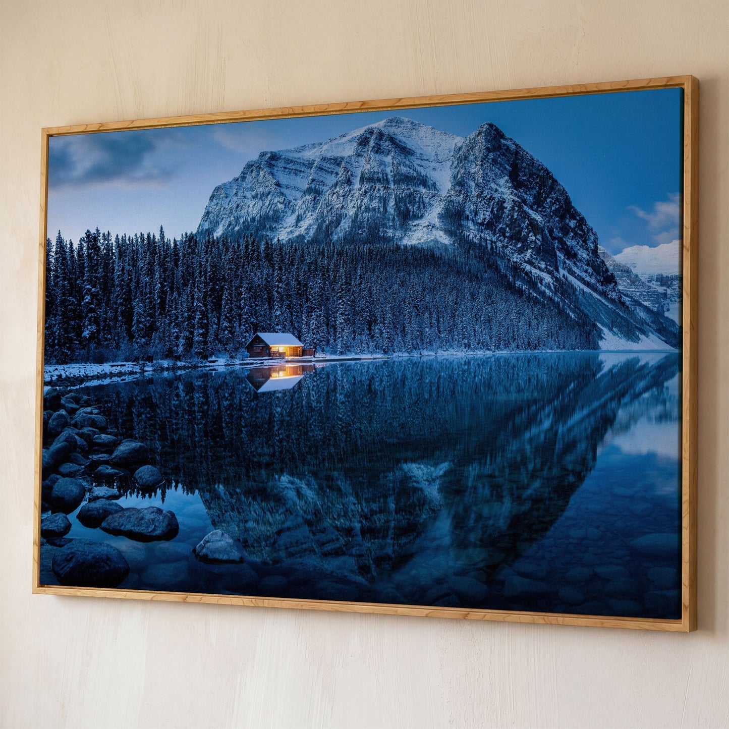 Lake Louise Winter Canvas with Lit Cabin and Mountain Reflection shown in white oak floating frame
