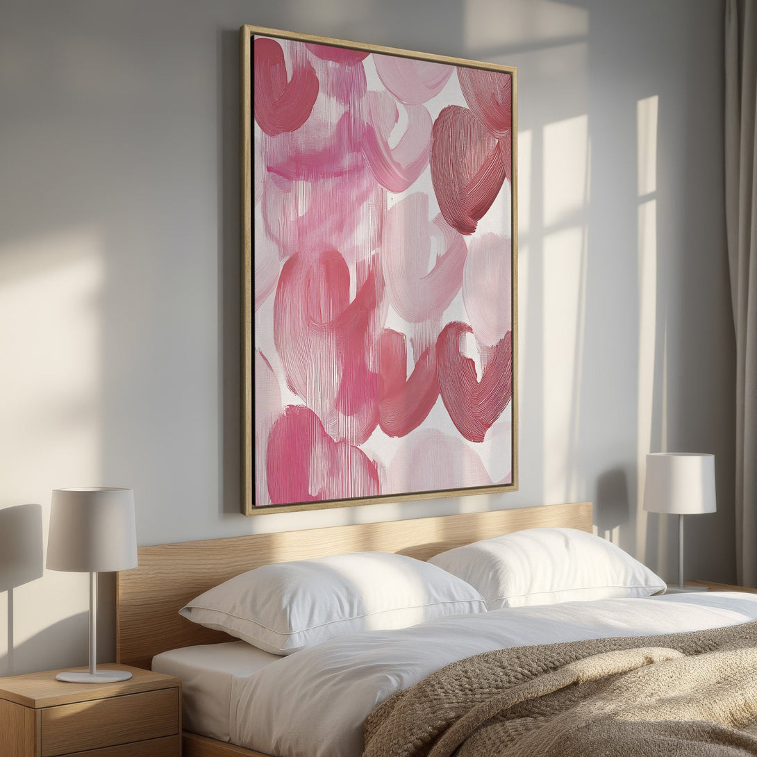 Framed Wall Art featuring abstract pink brushstrokes. Modern art canvas print in a bedroom with a warm, inviting color palette. Perfect for home decor.