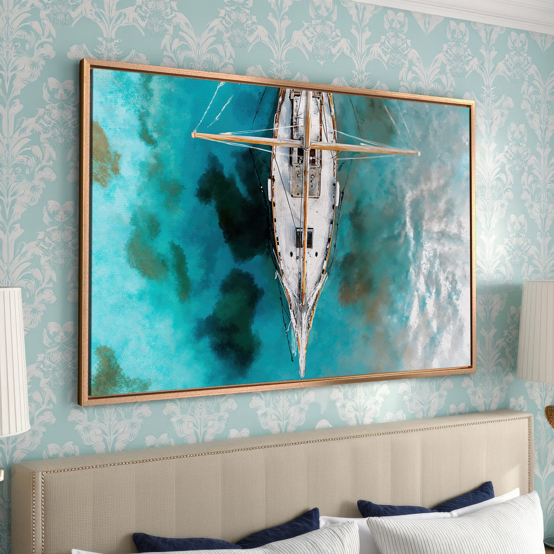 Framed Wall Art: Aerial view of a sailboat on turquoise water. Coastal art piece with a gold frame, perfect for bedroom decor. Blue and gold color palette.