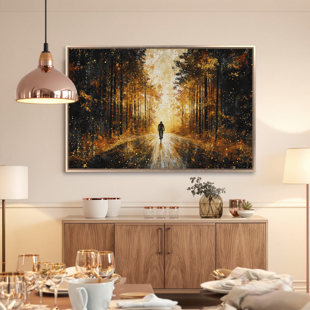 Framed Wall Art: Cyclist in a forest painting. Warm gold and black color palette. Perfect for adding a touch of nature to your home decor.