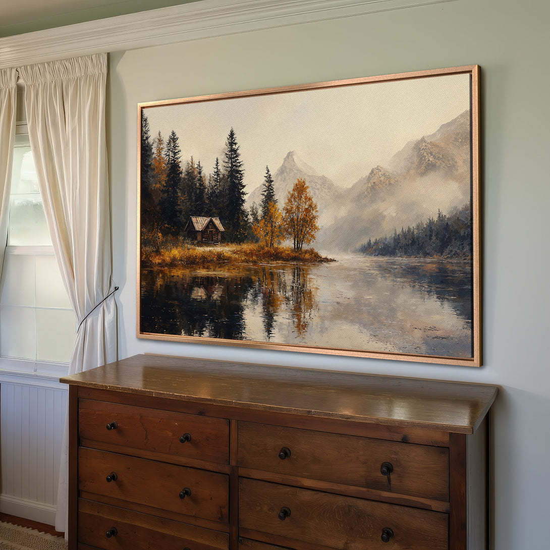 Framed Wall Art featuring a serene landscape with a cabin, lake, and mountains. Warm autumn color palette. Perfect for adding a touch of nature to your home.