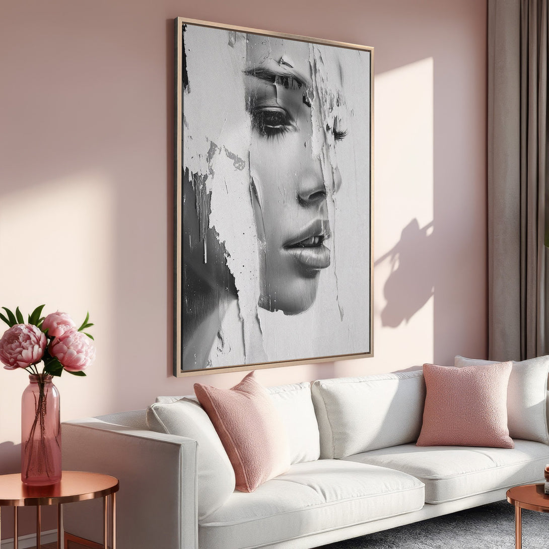 Framed Wall Art of a woman's face in a modern, abstract style. Black and white artwork with a gold frame, set against a soft pink interior.