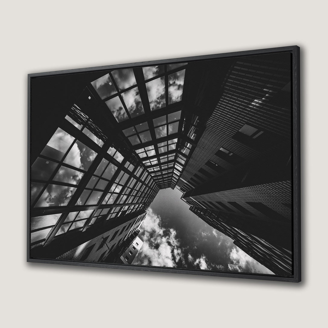 Framed Wall Art: Dramatic black and white cityscape Canvas Print. Modern architectural photography with a striking perspective and moody sky.