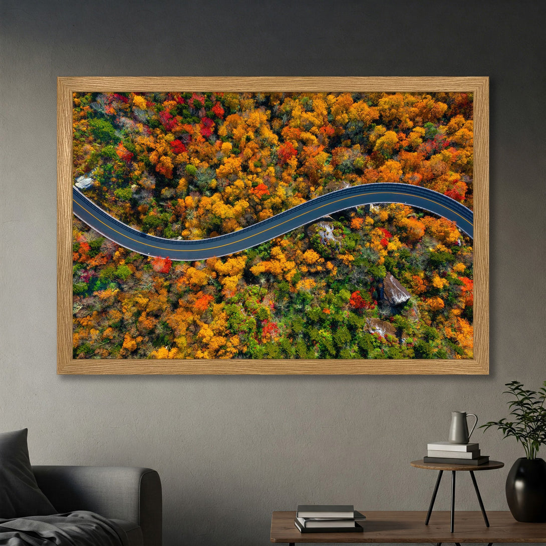 Framed Poster of scenic winding road through vibrant autumn forest. Warm color palette of orange, red, and green. Perfect wall art!