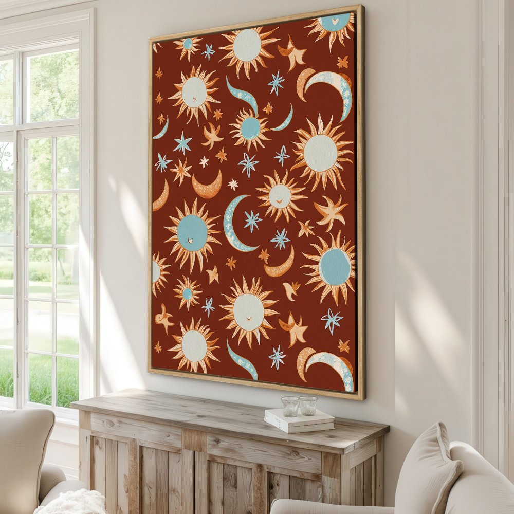 Framed Wall Art featuring a whimsical celestial pattern of suns, moons, and stars in a warm terracotta, blue, and orange color palette. Perfect for boho decor!