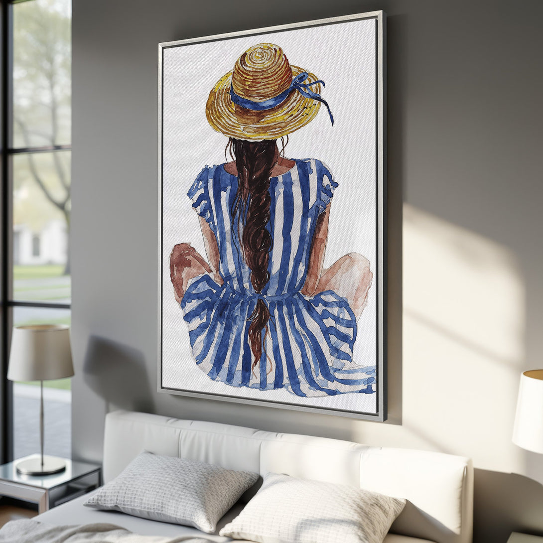 Framed Wall Art featuring a watercolor woman in a straw hat and blue striped dress. Coastal style art with a serene, blue and white color palette. Perfect for bedroom decor.
