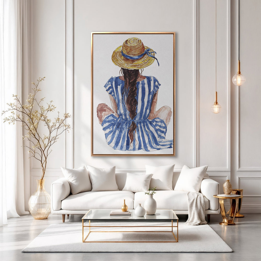 Framed Wall Art featuring a watercolor painting of a woman in a hat and blue striped dress. Coastal style art with a neutral and blue color palette.
