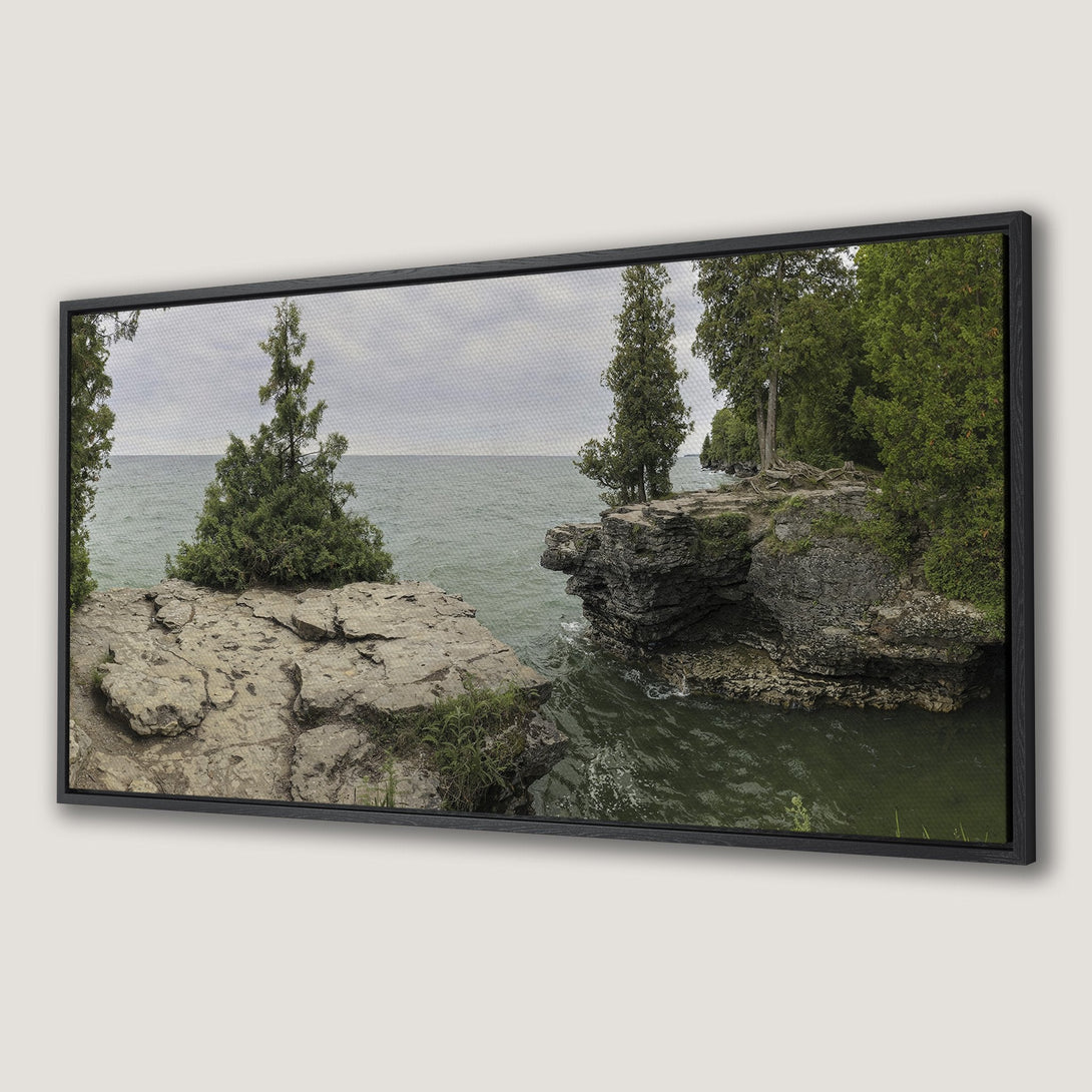 Framed Wall Art: Serene landscape Canvas Print featuring rocky cliffs, evergreen trees, and tranquil water in a muted green and gray palette. Bring nature indoors!