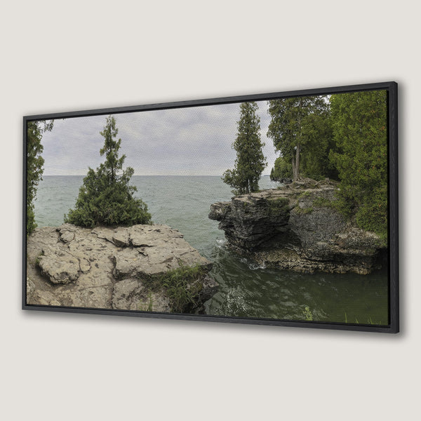 Framed Wall Art: Serene landscape Canvas Print featuring rocky cliffs, evergreen trees, and tranquil water in a muted green and gray palette. Bring nature indoors!
