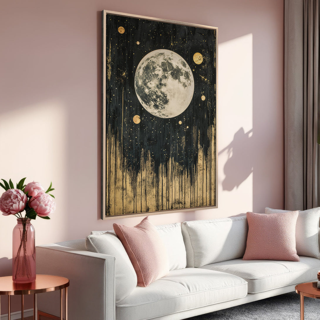 Framed Wall Art: Abstract moon canvas print in gold and black, displayed in a modern living room with a soft pink and neutral color palette.