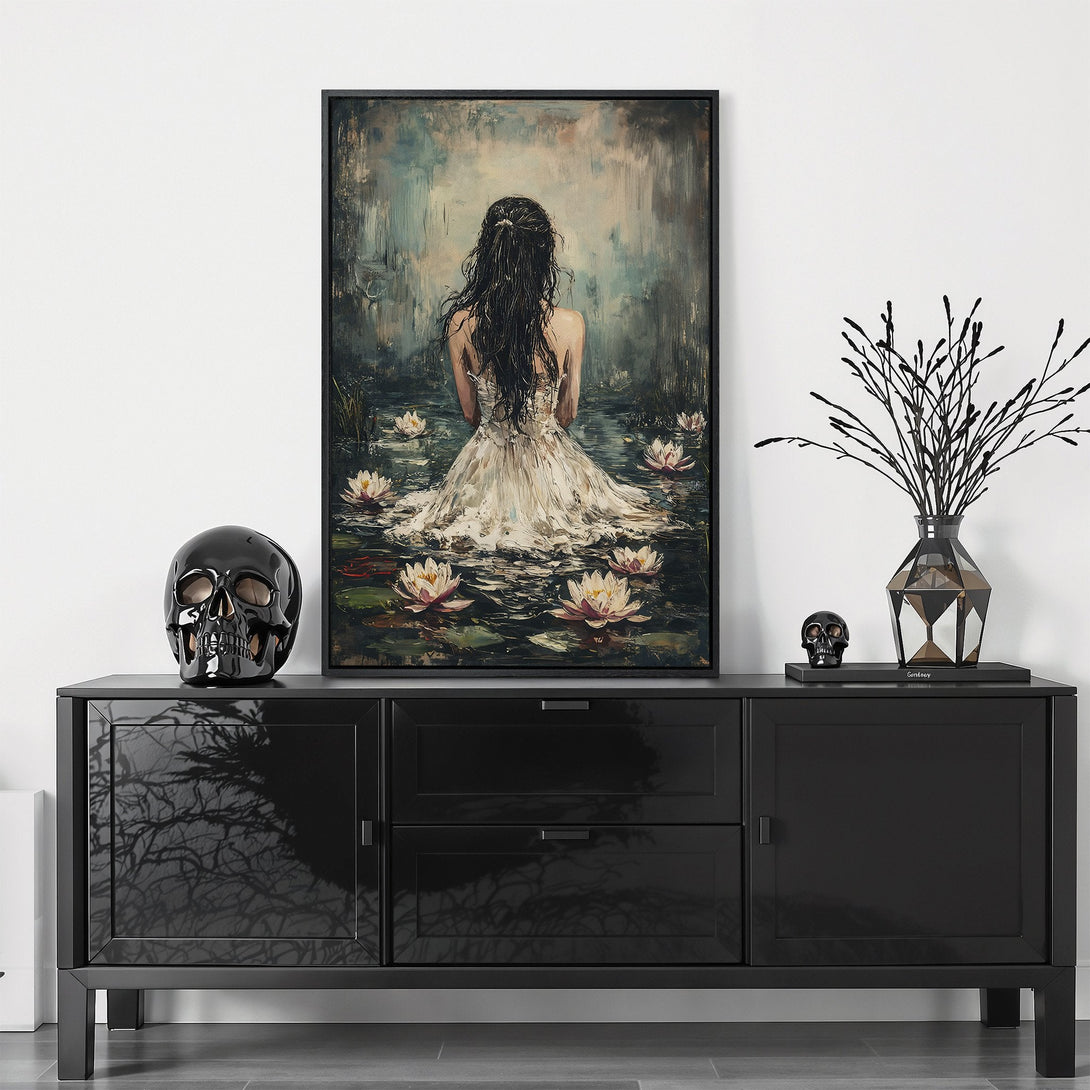 Framed Wall Art: Woman in white dress amidst lily pads. Serene, artistic style with neutral tones and a touch of dark contrast. Perfect for elegant decor.