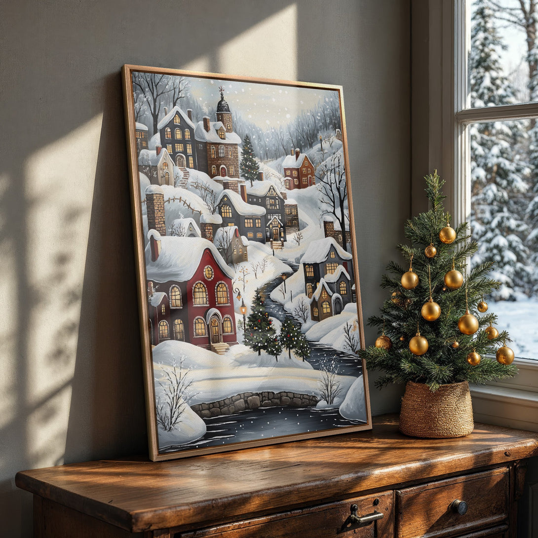 Framed Wall Art of a snowy village scene. Charming winter art with a warm color palette, perfect for holiday decor. Bring the cozy vibes home!