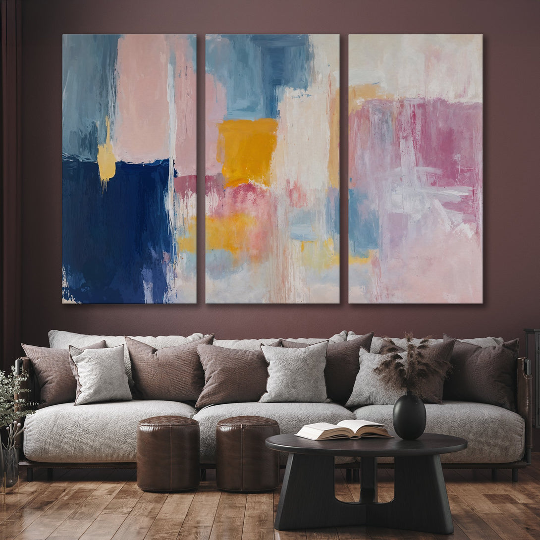 Abstract Canvas Print triptych in a modern living room. Features a colorful palette of blues, pinks, and yellow. Perfect for adding art to your home!