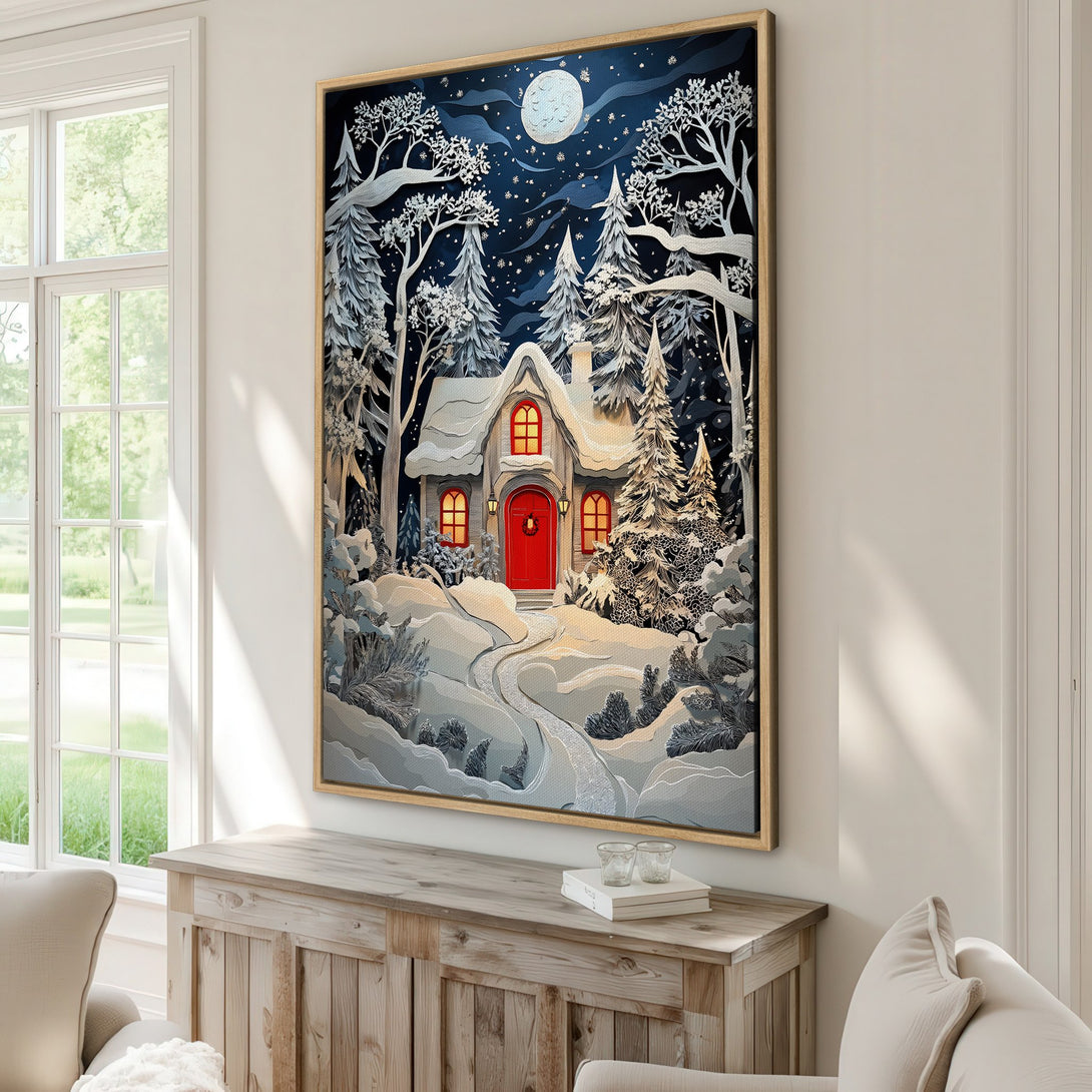Framed Wall Art featuring a winter cabin scene with a snowy landscape. The artwork is in a paper-cut style with a blue, white, and red color palette. Perfect for cozy decor.