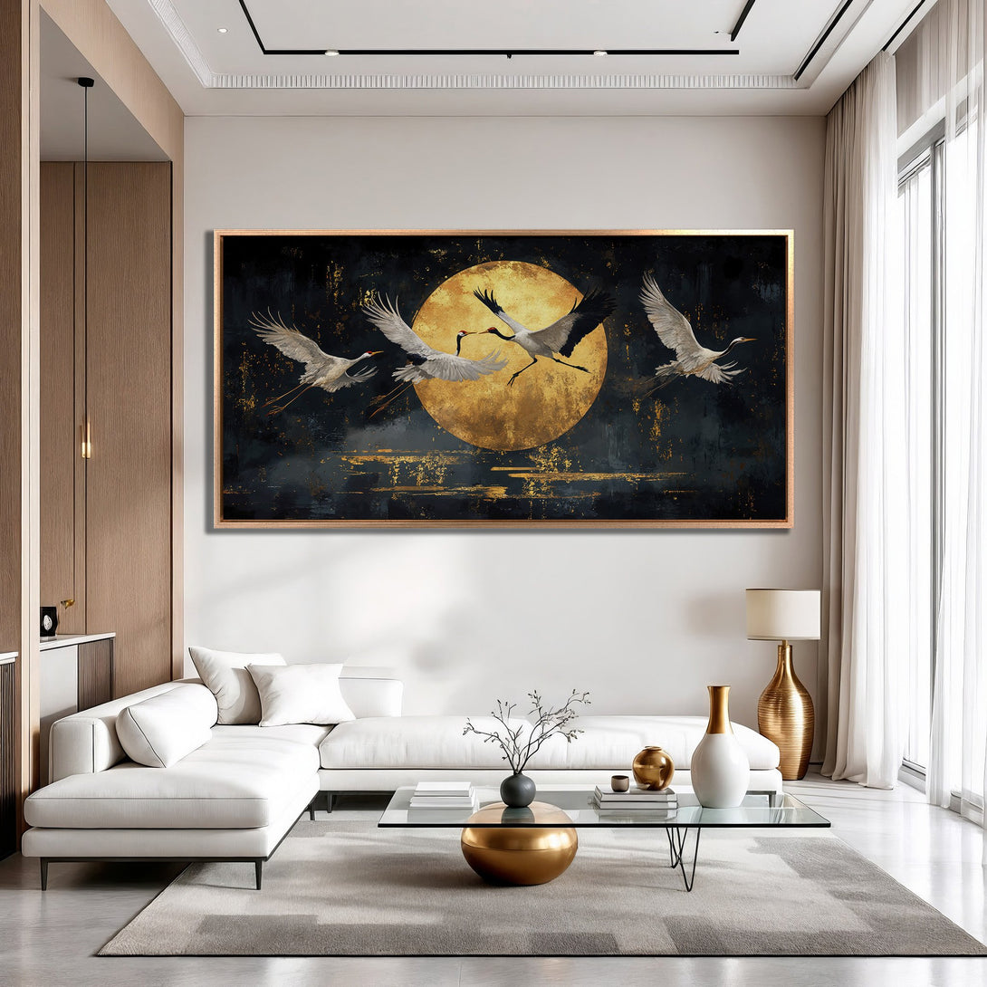 Framed Wall Art: Cranes in flight over a golden moon. Modern, abstract style with a dark, gold, and neutral color palette. Perfect for living room decor.