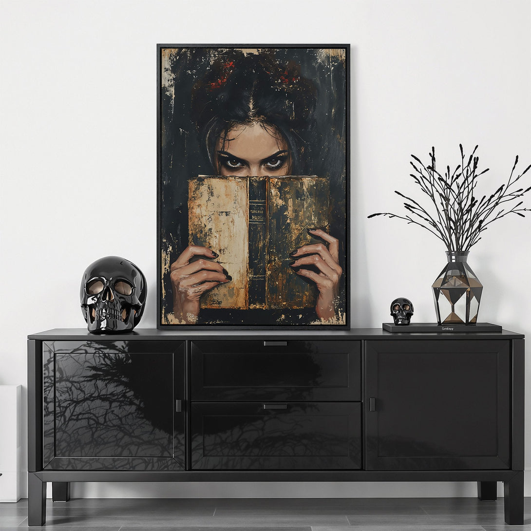 Framed Wall Art: Dark, moody portrait of a woman with piercing eyes behind a book. Dramatic art with a black, gold, and brown color palette. Perfect for gothic decor.