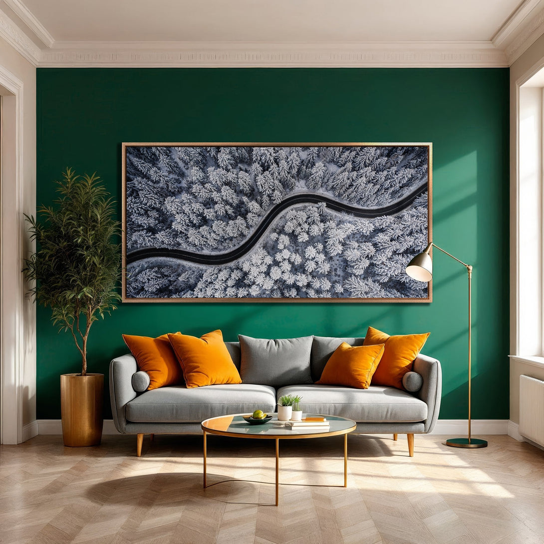 Framed Wall Art: Aerial view of snowy forest road in a modern living room. Cool blues & whites pop against the green wall, creating a stylish, inviting space.