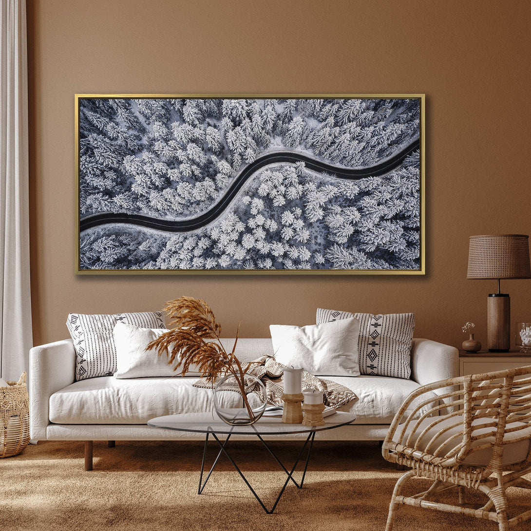 Canvas Print of a winding road through a snowy forest. Stunning aerial view in cool blue and white tones. Perfect wall art for your home.