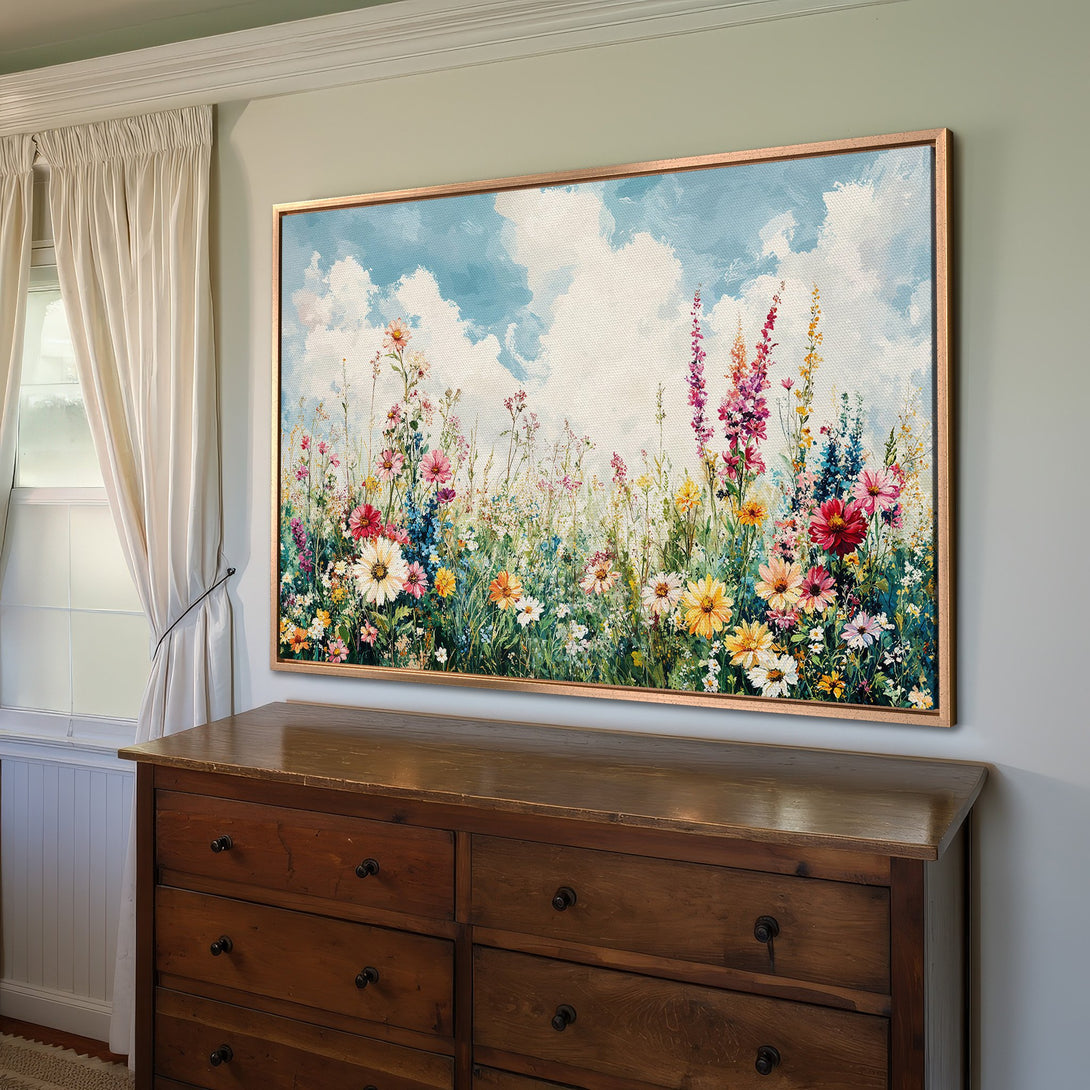 Framed Wall Art: Colorful wildflower meadow canvas print in a bright, airy room. Features a vibrant floral scene with blue, pink, and yellow hues.