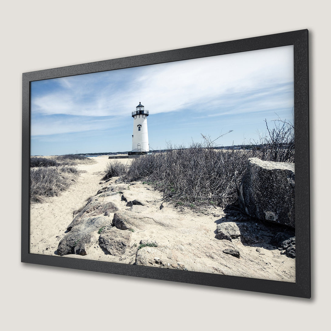 Framed Poster featuring a lighthouse on a sandy beach. Coastal landscape art in muted blue and neutral tones. Perfect wall decor!