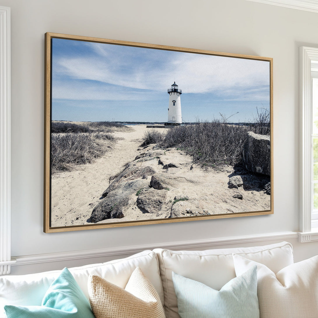 Framed Wall Art: Coastal lighthouse Canvas Print in neutral tones. Bring the beach home with this serene artwork featuring a blue sky and sandy path.