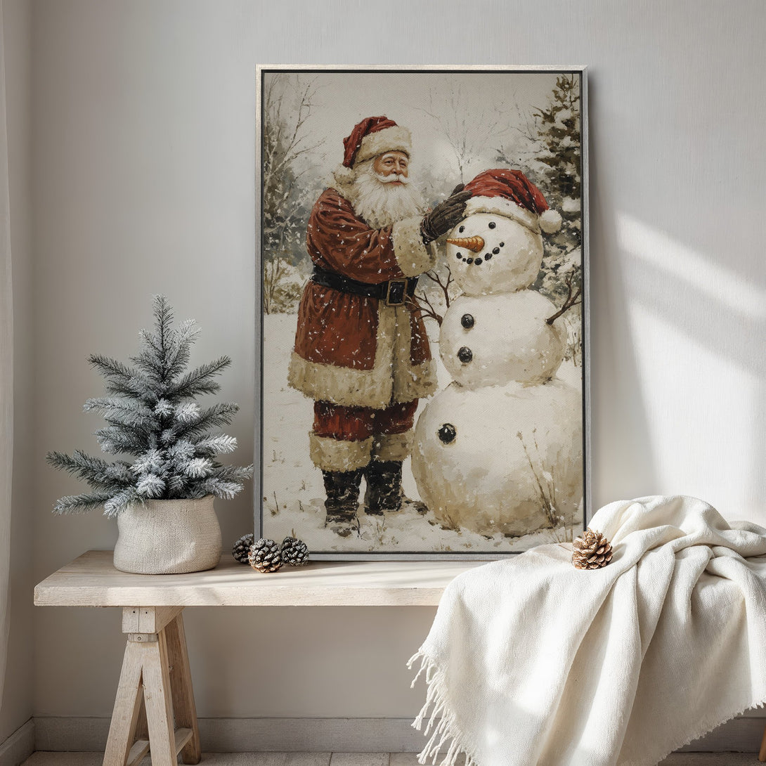Framed Wall Art featuring Santa Claus building a snowman in a vintage style. Warm red and white color palette, perfect for Christmas decor.