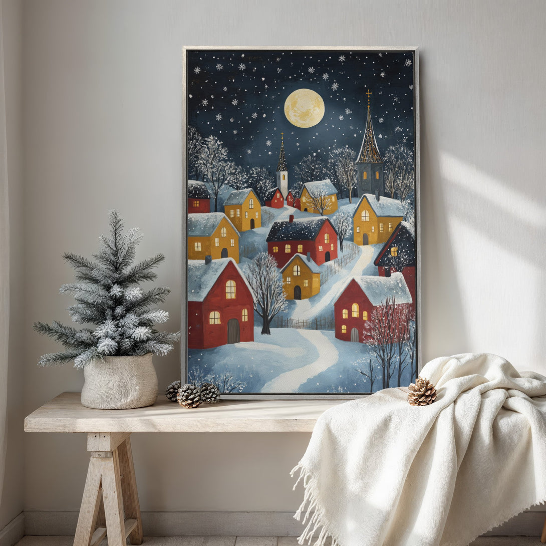 Framed Wall Art: Winter village scene Canvas Print with a cozy, whimsical style. Features a snowy landscape with red and yellow houses under a starry night sky.