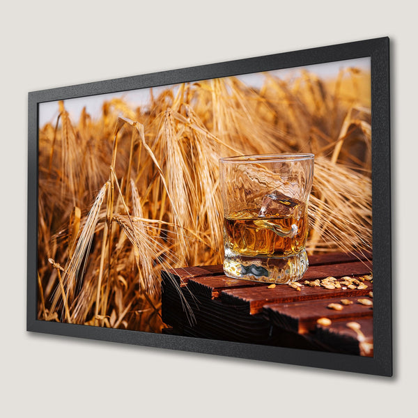 Framed Poster of whiskey with ice on a wooden surface in front of a wheat field, warm tones, rustic style.