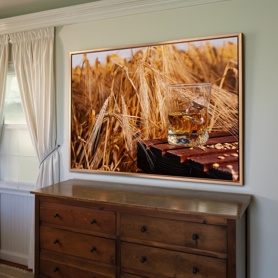 Framed Wall Art: Whiskey on a rustic wood table with wheat field background. Warm, earthy tones create a cozy, inviting atmosphere. Perfect for home decor.