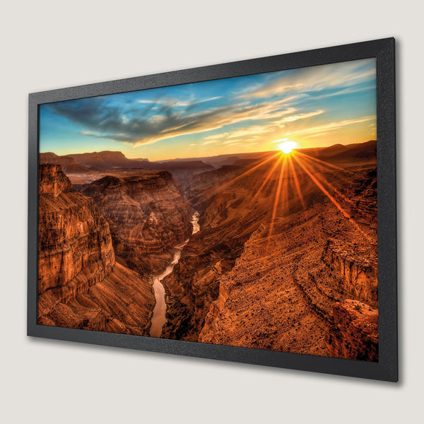 Framed Poster of Grand Canyon sunset. Vibrant landscape art with warm orange, yellow, and blue hues. Perfect wall decor.
