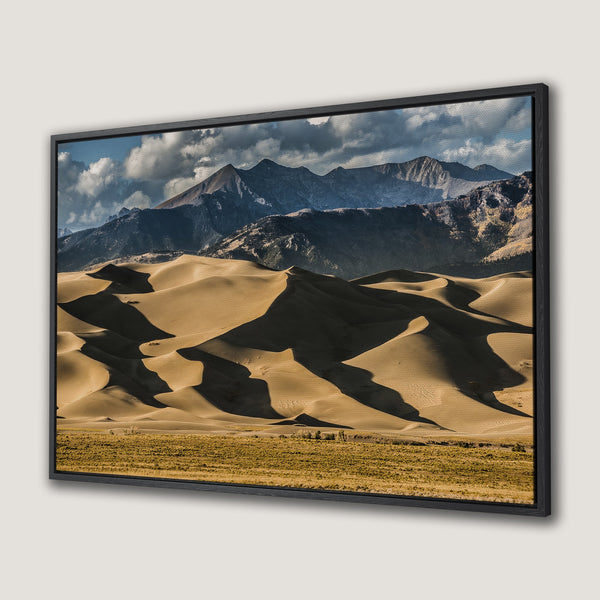 Framed Wall Art: Stunning landscape Canvas Print of sand dunes and mountains, featuring warm earth tones with blue sky and dramatic shadows. Elevate your home decor!