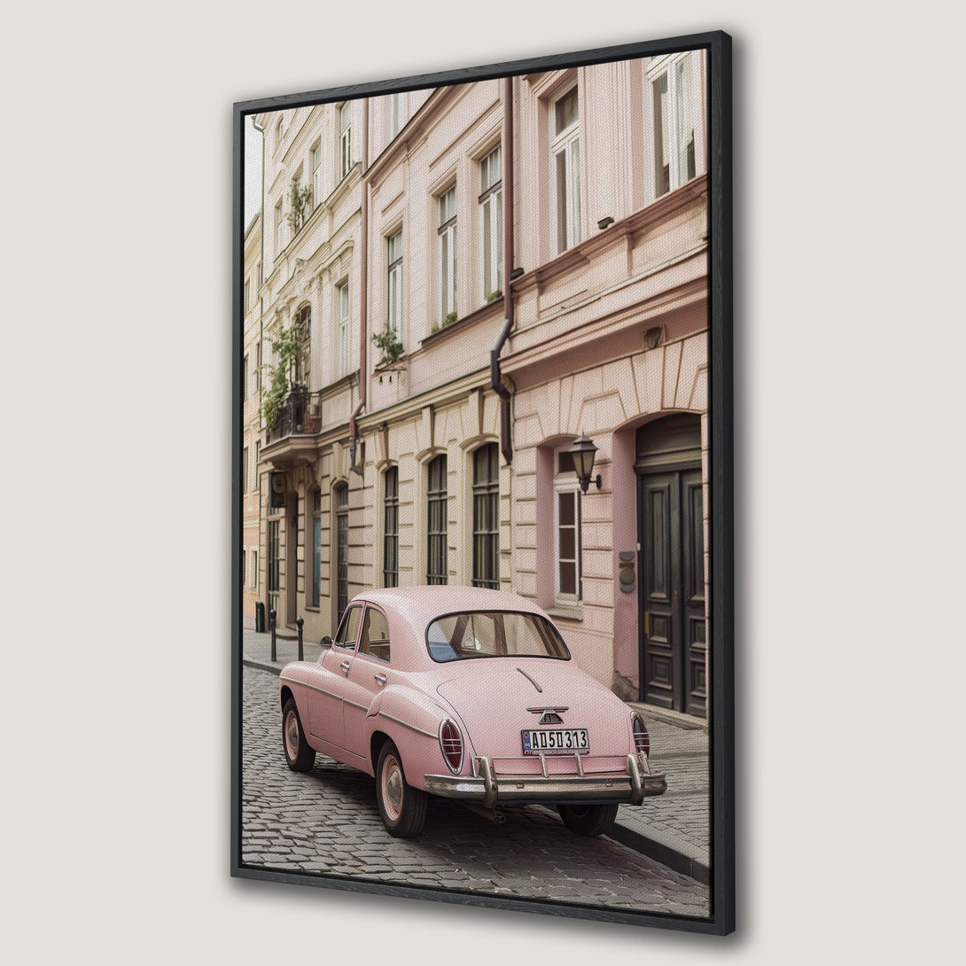 Framed Wall Art: Vintage pink car parked on a cobblestone street in a European town. Soft, pastel color palette. Perfect for adding charm to your space.