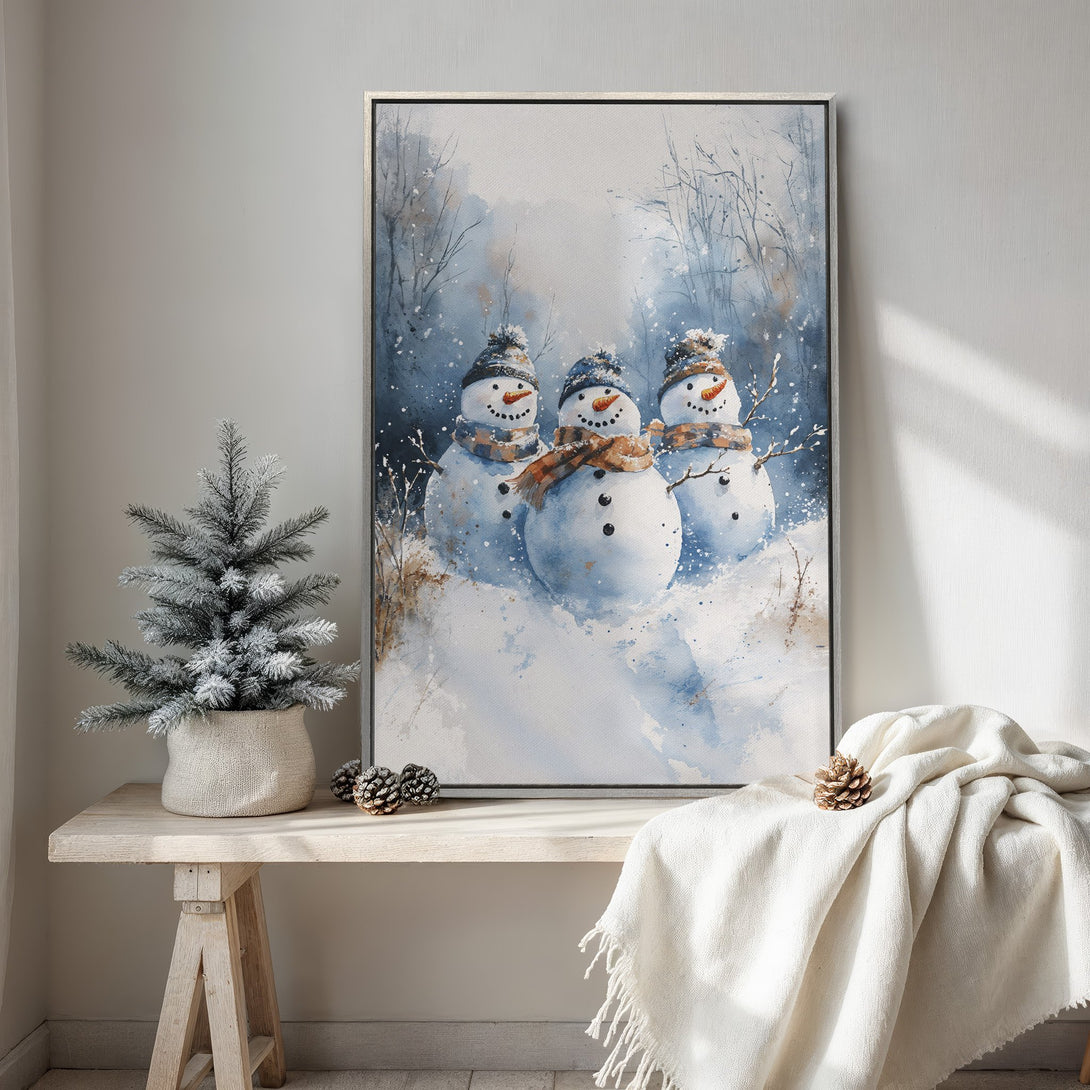 Framed Wall Art featuring watercolor snowmen in a winter scene. Blue and white color palette, perfect for holiday decor. Add a touch of winter charm!