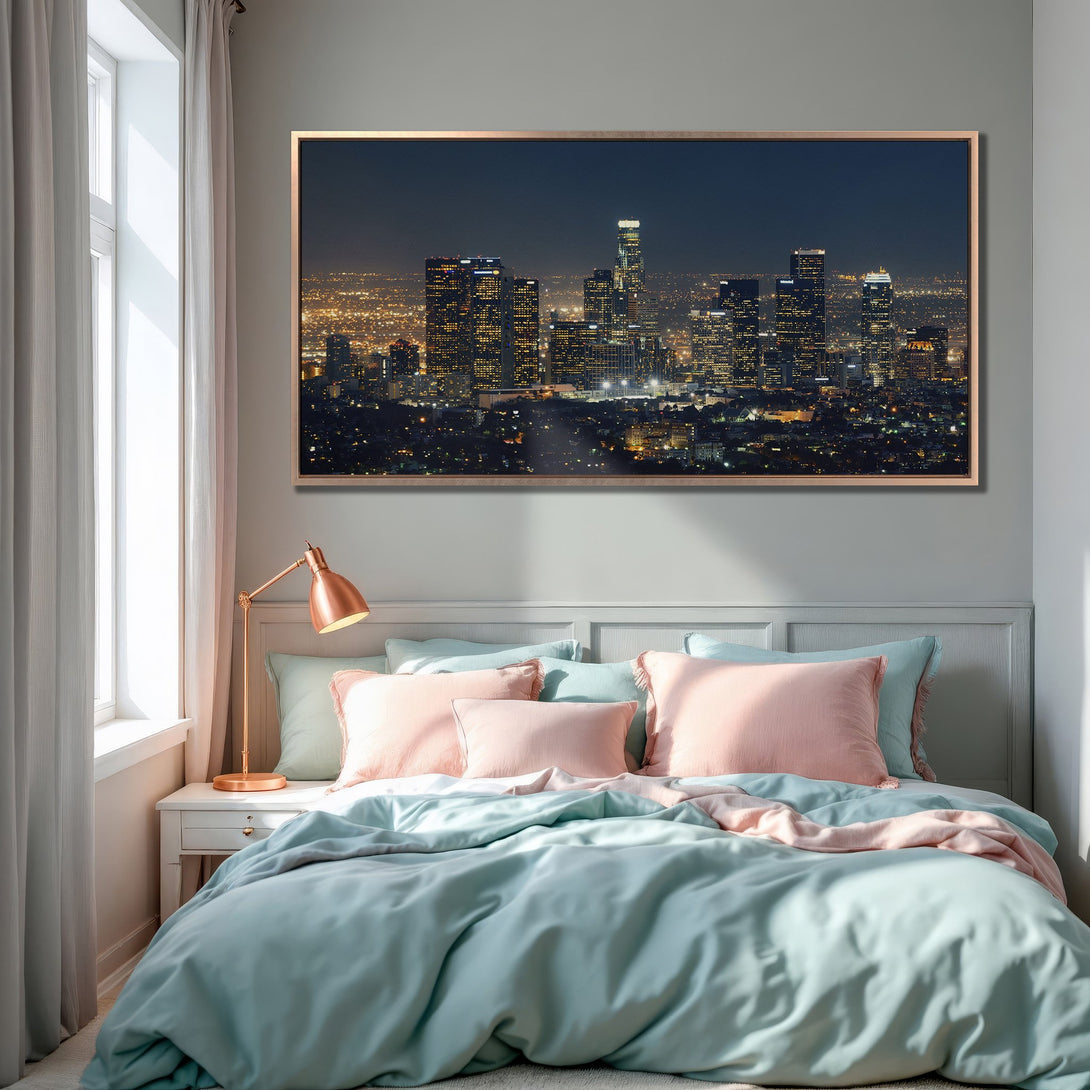 Framed Wall Art of Los Angeles skyline at night, displayed in a bedroom. Modern decor with a cool blue and pink color palette.