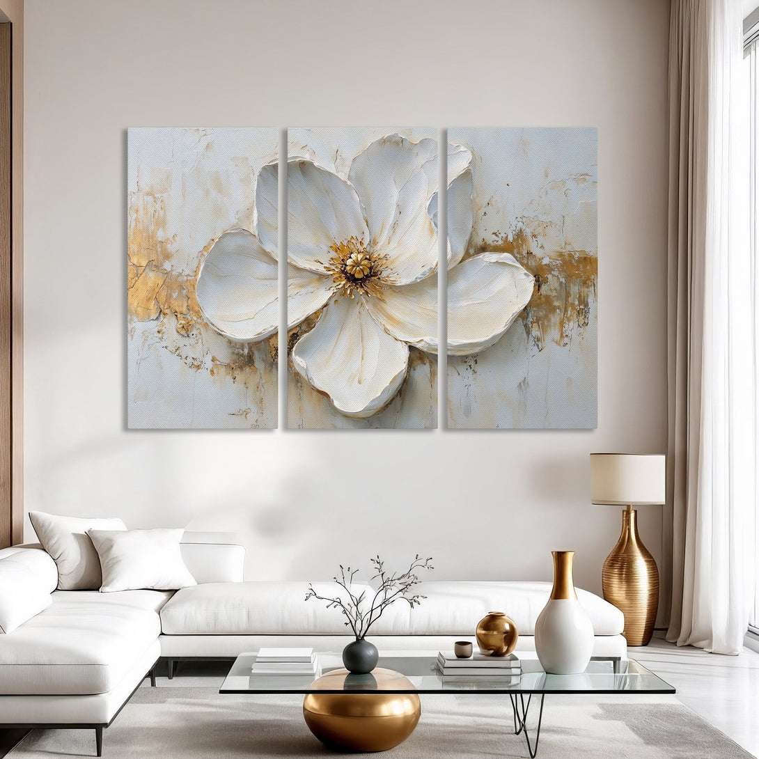 Canvas Print of a textured white flower painting with gold accents, displayed in a modern living room. Neutral color palette.
