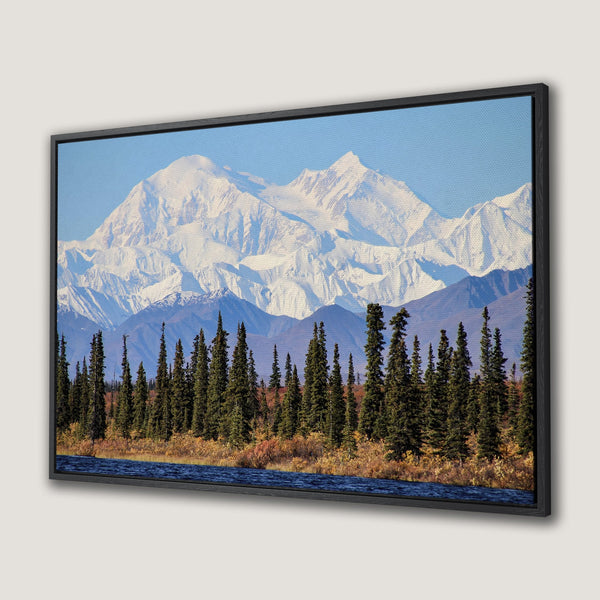 Framed Wall Art: Majestic mountain landscape Canvas Print. Featuring snowy peaks, evergreen trees, and a blue river. Earthy tones create a serene, natural aesthetic.