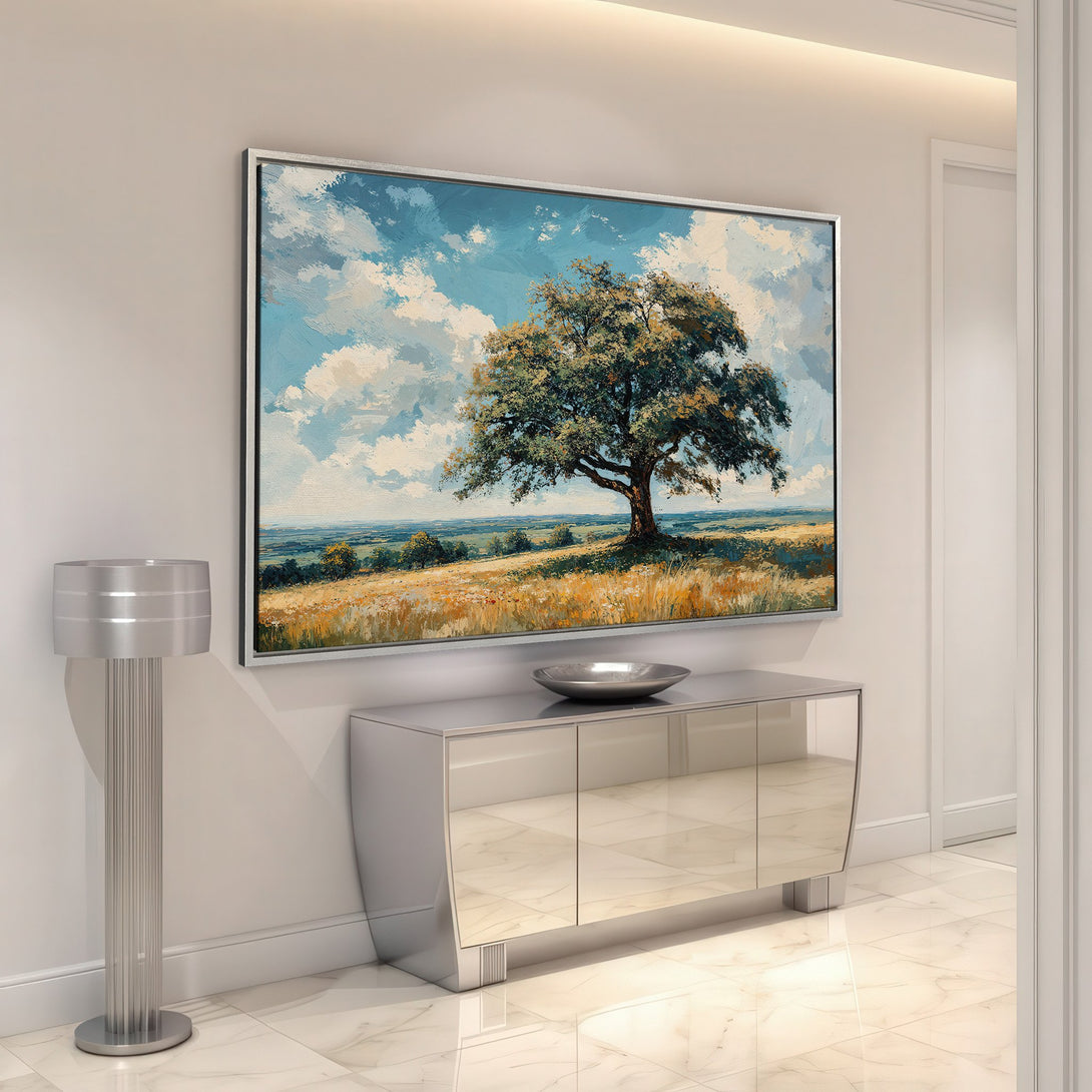 Framed Wall Art featuring a landscape painting with a large tree, blue sky, and warm color palette, enhancing interior decor.