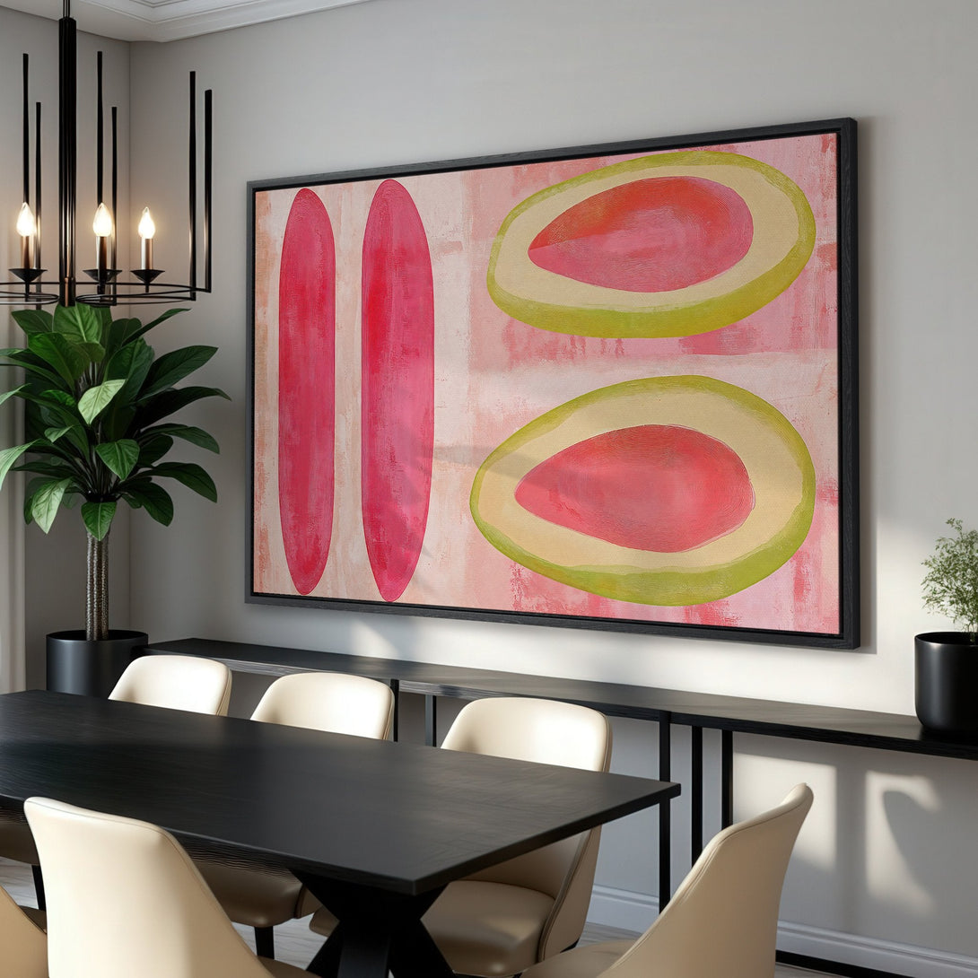 Framed Wall Art featuring abstract pink and green fruit shapes. Modern art canvas print in a dining room setting. Perfect for adding a pop of color.