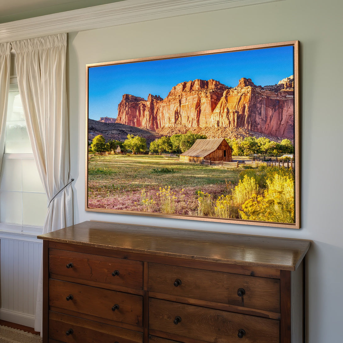 Framed Wall Art featuring a stunning landscape of a barn and red rock mountains, with warm, earthy tones. Perfect for adding a touch of nature to your home.