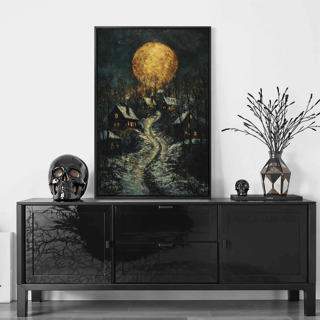 Framed Wall Art featuring a mystical landscape with a golden moon, houses, and a snowy path. Dark, moody color palette perfect for adding a touch of mystery.
