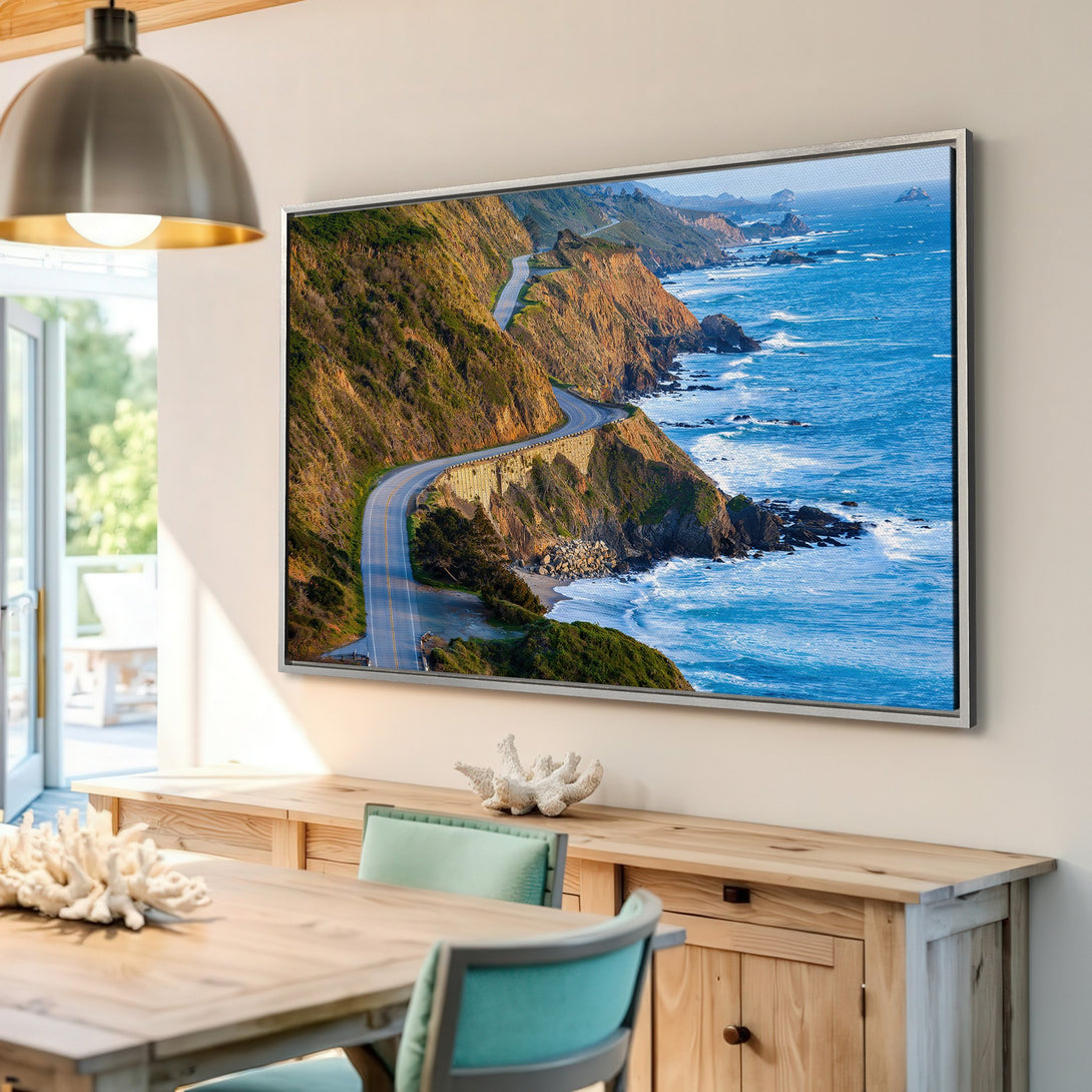 Framed Wall Art of a scenic coastal road. Earthy tones of green and brown meet vibrant blue ocean. Bring the beauty of nature into your home.