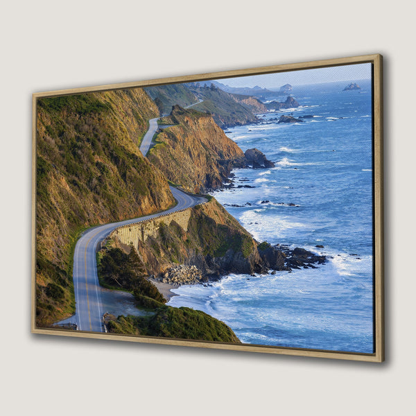 Framed Wall Art: Coastal highway canvas print. Scenic landscape with ocean and cliffs in warm tones of blue, green, and orange. Perfect wall decor!