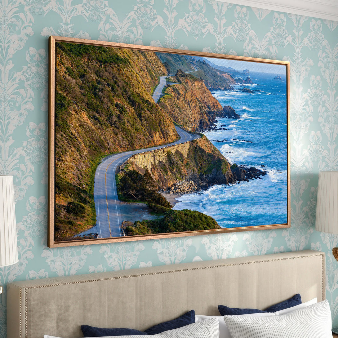 Framed Wall Art of scenic coastal highway. Earthy tones of brown, green, and blue create a stunning landscape. Perfect for adding a touch of nature to your home.