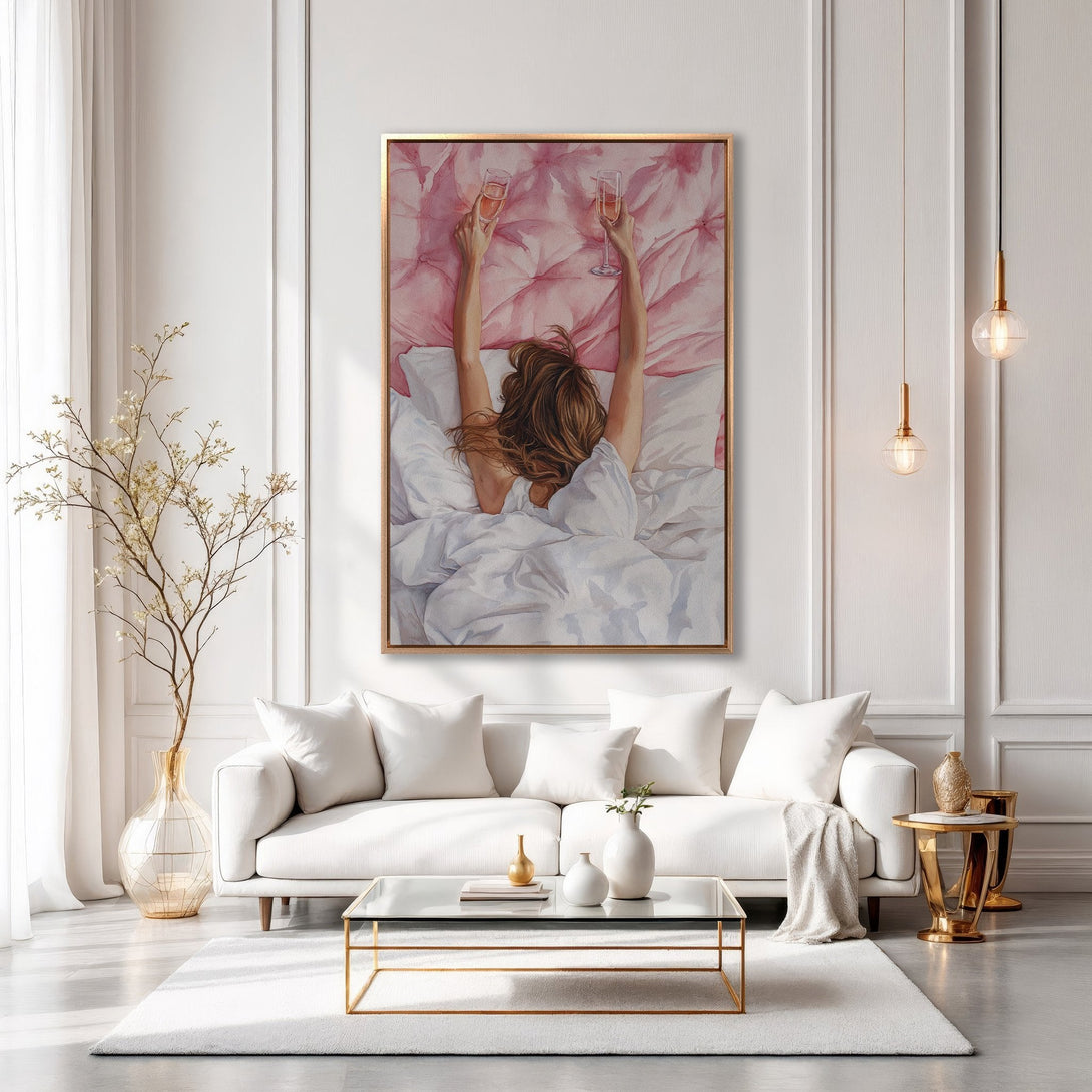 Framed Wall Art: Woman in bed with champagne, watercolor style, blush pink and gold tones, displayed in a modern, elegant interior.