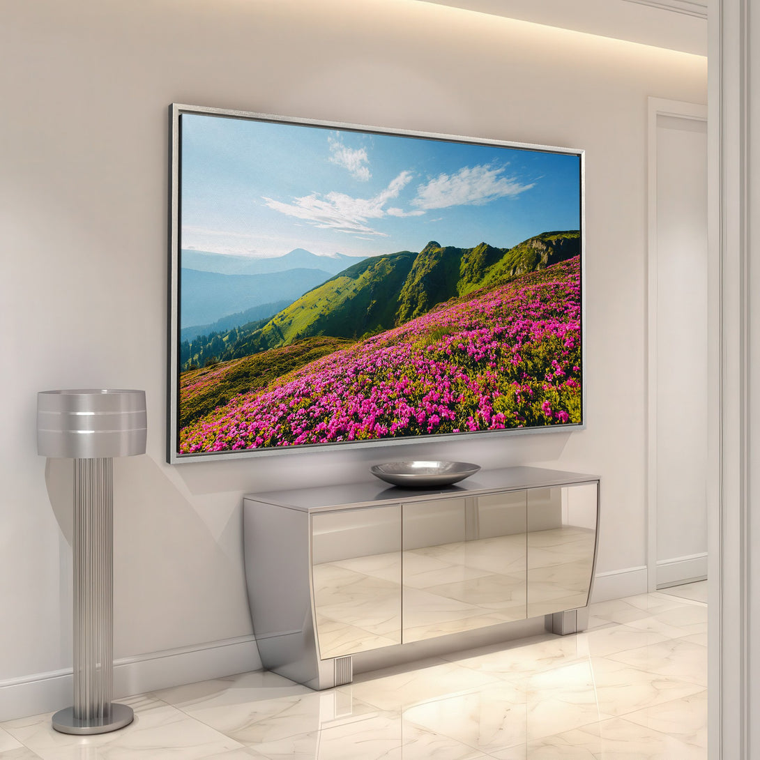Framed Wall Art: Mountain landscape Canvas Print with vibrant pink flowers, green hills, and blue skies. Modern home decor in a bright, natural color palette.