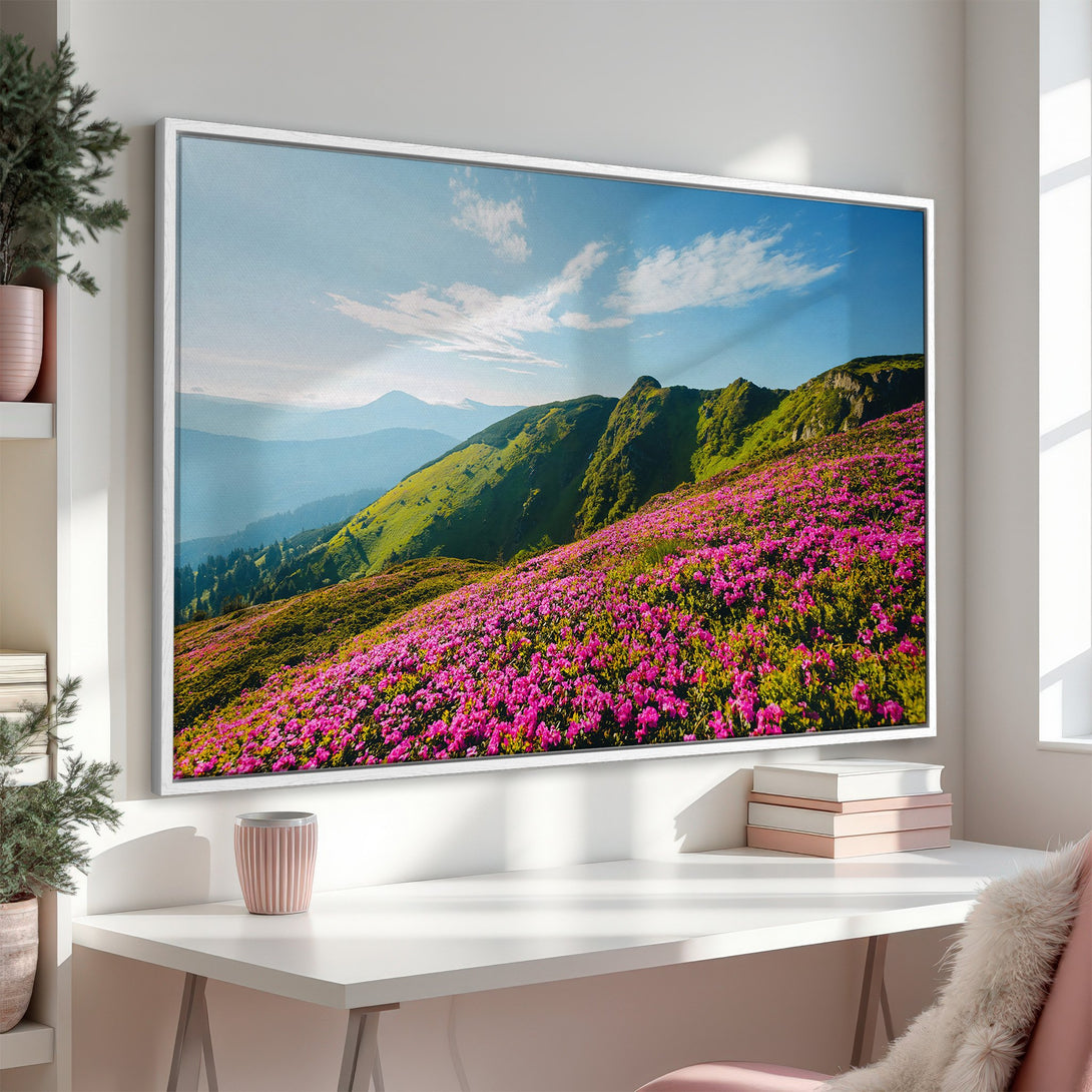 Framed Wall Art: Stunning mountain landscape Canvas Print. Vibrant pink flowers, lush green hills, and blue sky. Perfect for adding a touch of nature to your home.