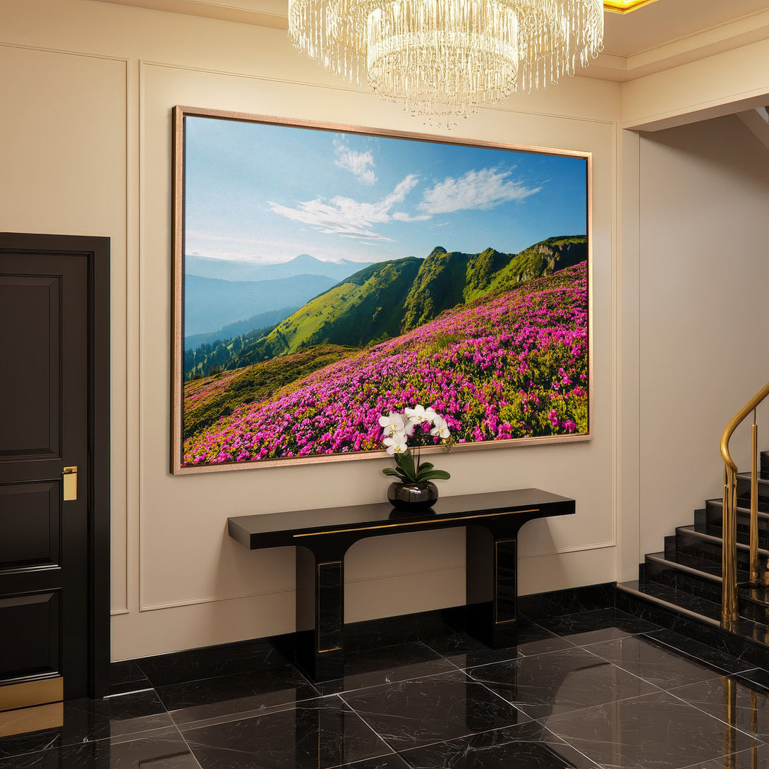 Framed Wall Art: Mountain landscape Canvas Print with vibrant pink flowers, green hills, and blue sky. Adds a touch of nature to any interior.
